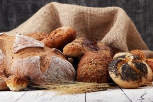 Assortment of baked bread and bread rolls on wooden table background