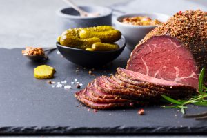 Roasted beef, pastrami on slate cutting board. Copy space